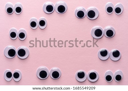 Creative layout of many googly eyes on pink background. Minimal concept.