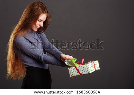 Image of happy girl opening and looking into gift box and wondering