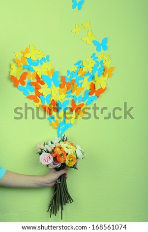 Paper butterflies fly out of flowers on green wall background