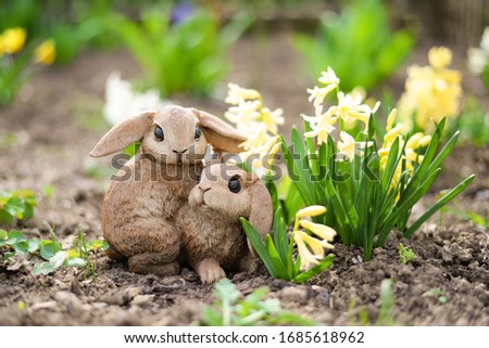 a picture of gypsum rabbits ine garden, standing near the hyacinth