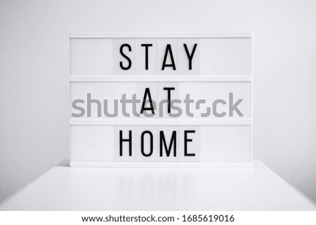 coronavirus pandemic and quarantine concept - light box with stay at home message over white background