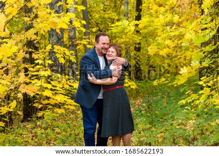 Husband and wife in the maple autumn forest walk, hug, laugh, rejoice
