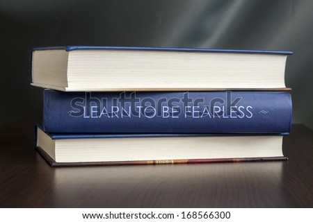 Books on a table and one with " Learn to be fearless " cover. Book concept.