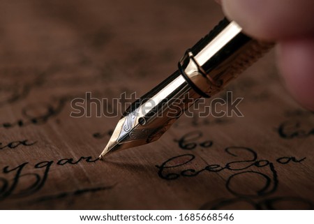 fountain pen in the hand with paper with ink text on the wooden desk closeup