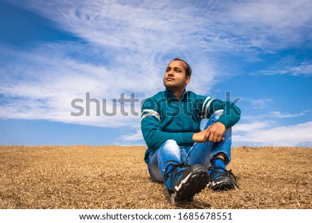 man posing at the beautiful yellow grass with blue sky background
