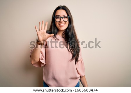 Young brunette elegant woman wearing glasses over isolated background showing and pointing up with fingers number five while smiling confident and happy. Royalty-Free Stock Photo #1685683474