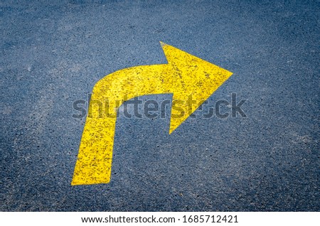 Yellow arrow on black pavement pointing right