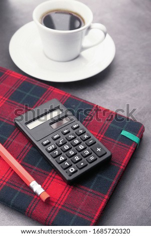pencils, calculator notepad, and tea t on table at early morning 
