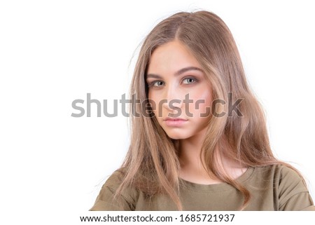 Pretty young girl with long brunette hair looks at camera over white background