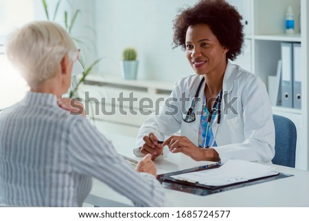 A female doctor sits at her office and examining elderly female patient Royalty-Free Stock Photo #1685724577