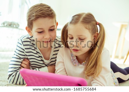 Two siblings children having online lesson with laptop at home during quarantine