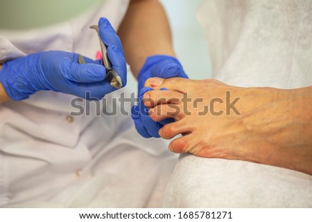 Close-up nail care by a pedicure specialist in a beauty salon. Pedicure transparent cuticle professional scissors for pedicure.