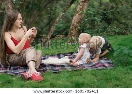 Young mother taking pictures of their children on phone. Picnic with the whole family