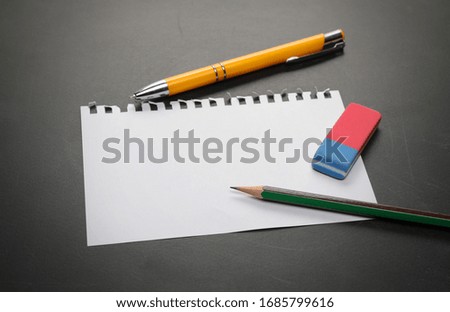 Blank note paper with pencil
on blackboard, chalkboard black