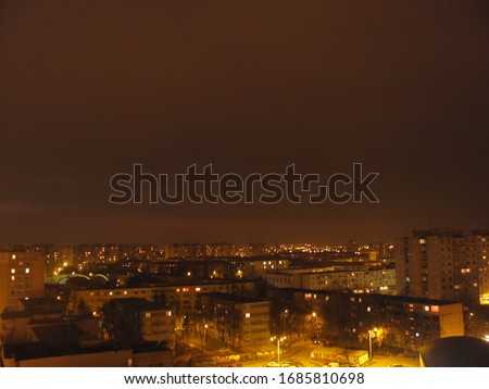 Woman fading out of a shot with long exposure, top of a tower block, yellow city lights