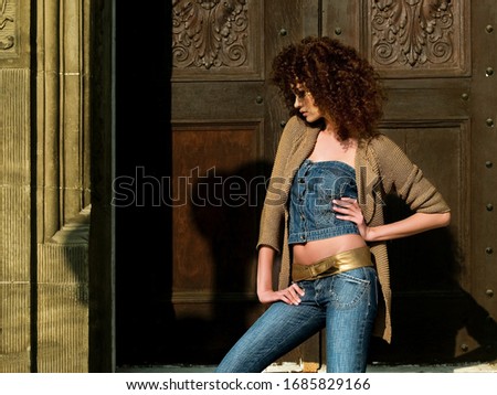 Cool, curly haired, brunette model posing in blue jeans. Royalty-Free Stock Photo #1685829166