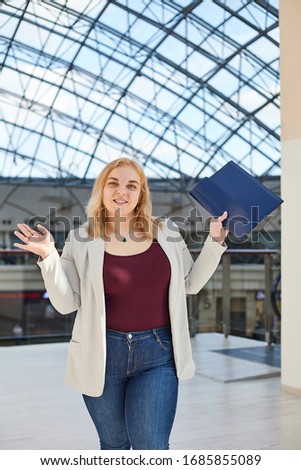 blonde girl in a jacket stands with a folder in a business center 