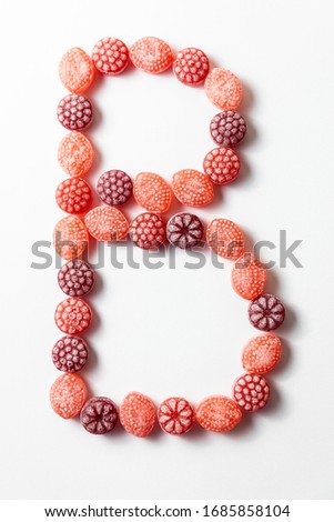 Letter B of alphabet homemade by multicoloured berry candies on the white background