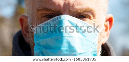 Middle-aged, redhead man in one-use surgical mask standing outdoor on sunny day, close-up. Infection risk protection kit. Stopping coronavirus death toll. Rapidly spreading pandemic from Wuhan, China. Royalty-Free Stock Photo #1685861905