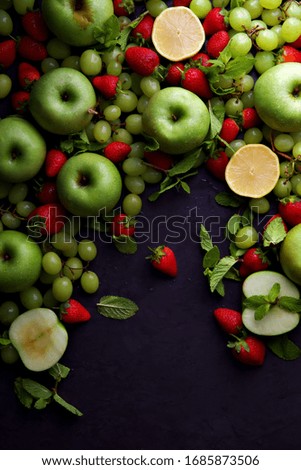 Fresh fruits including green apples, green grapes and red strawberries with lemon.  Portrait flat lay background.