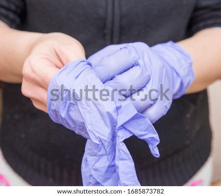 Woman pulling surgical gloves on hands
