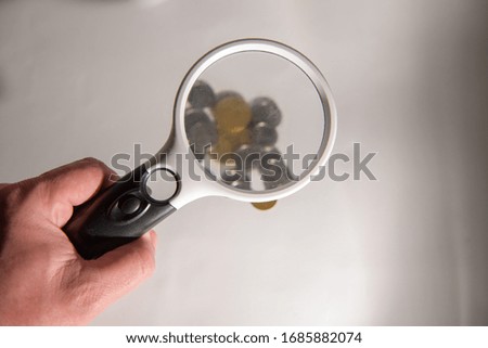 Man to look through the magnifying glass of coins
