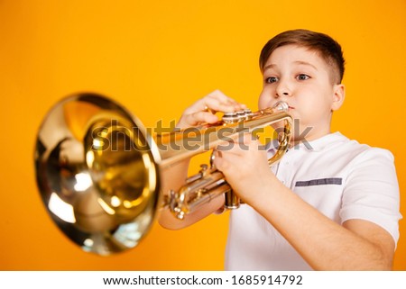 A cheerful boy plays the pipe blowing his cheeks. Humor playing a wind instrument Royalty-Free Stock Photo #1685914792