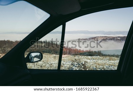 View through the passenger car window to the snowy mountains and mist in the valley