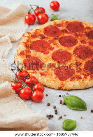 Fresh round baked Pepperoni italian pizza with tomatoes with basil on light kitchen table background. Space for text