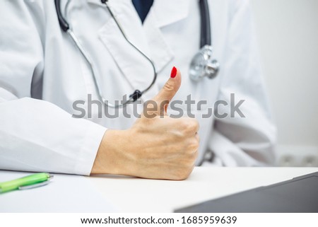 Closeup of a female doctor hand showing like thumb up sign and filling in diagnosis of patient on a paper. Coronavirus test and prevention concept. Epidemic pandemia of covid-19 nCov2019
