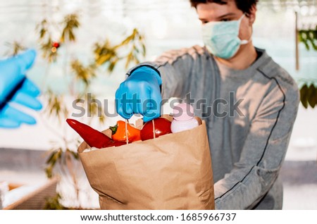 Volunteer carrying necessities for citizens in home self isolation.Young Man with bag of groceries for Senior people during Corona virus Pandemic.Town in quarantine due to Covid-19 flue infection Royalty-Free Stock Photo #1685966737