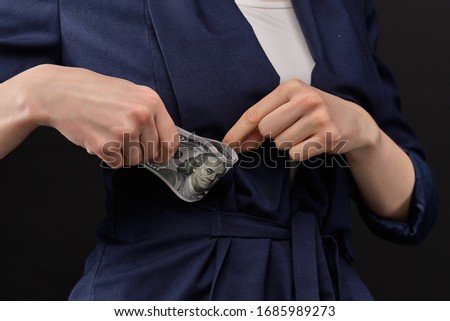 Girl in a jacket removes US dollars on a black background. Close up.