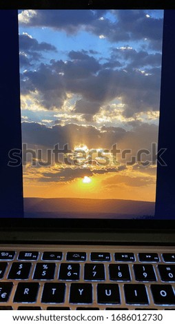 Work at home keyboard and screen with sunset image being retouched before uploading in stock photo