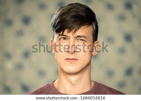 Portrait of a young man with dark hair with emotion of suspicion.