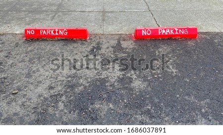 Red No Parking Sign Warning on Parking Lot Barrier Block with White Letters
