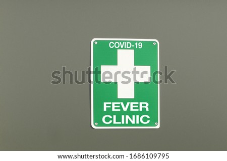green and white COVID-19 Fever Clinic sign on a building