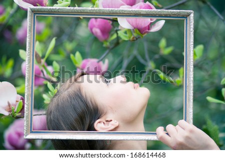 Beautiful young model framing herself with an old picture frame