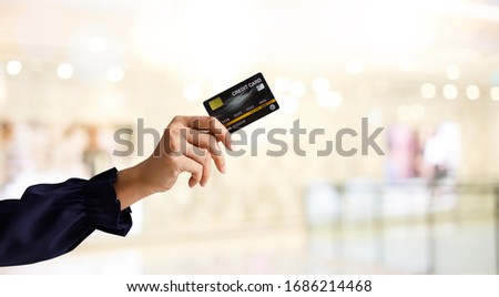 Business shopping ideas concept for web banner. Close up of woman hand holding credit card for shopping with abstract blur shopping mall background.