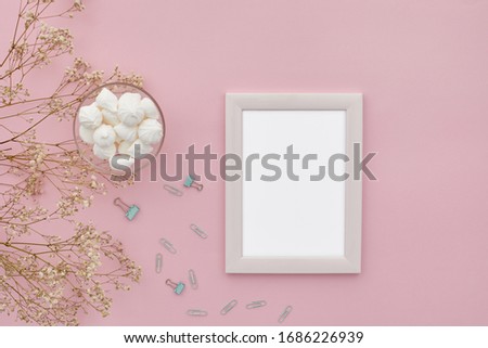 flat lay gypsophila flowers, photo frame and marshmallows on pink background, top view. empty space for text. mock up with copy space.
