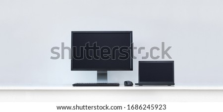 Clean white desk with computer screen and laptop.