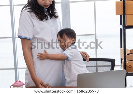 Asian young family help together feeding adorable cute girl at home, father making small business marketing online logistic home office, mother playing with child, parenthood duty multi task concept