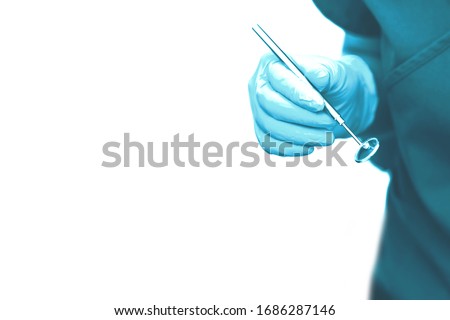 In the office of the dental clinic. The doctor holds tools for examination of teeth in blue sterile gloves.