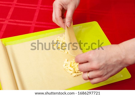 Traditional Brazilian food called "PASTEL" - Woman's hands rolling the dough with cheese. Close-up. Top view. Horizontal shot.
