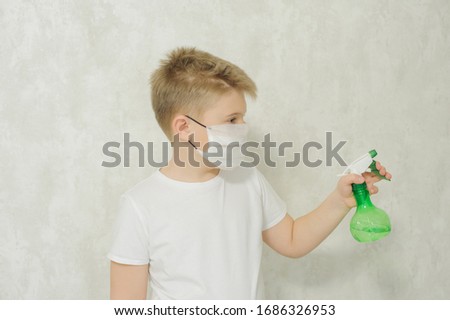 The boy in a protective medical mask sprays a disinfectant or antibacterial spray to prevent the spread of viruses and germs. Quarantine concept. Covid-19