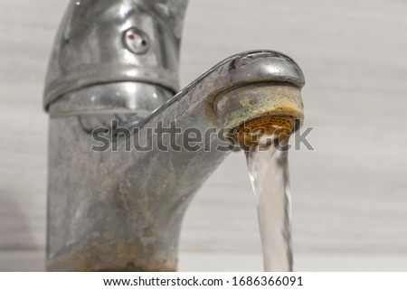 Old Bathroom Sink Faucet contaminated with calcium and grime. Hard water flows from an old tap aerator. Royalty-Free Stock Photo #1686366091