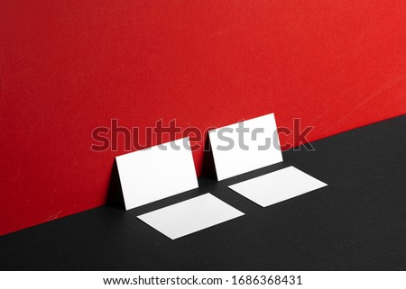 Blank white business cards on red and black paper background, copy space