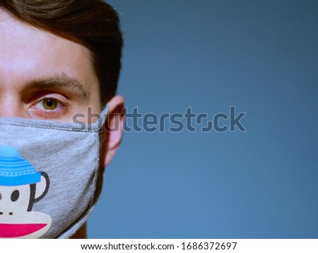 Closeup of a caucasian man face wearing funny monkey face protection mask with a brown eyes and hair, since new coronavirus outbreak for self protection.