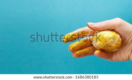 Easter eggs in hands on a blue background. Easter background. hand and egg in gold sparkles