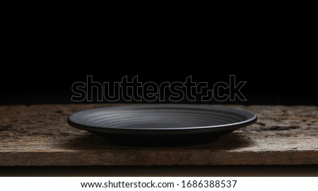 Black plate on wooden black background. Royalty-Free Stock Photo #1686388537