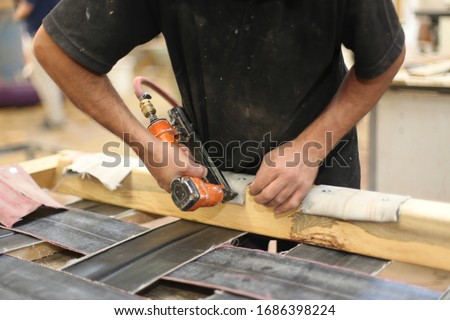 Profession, carpentry and woodwork concept.Upholstery workshop. Upholstery stapler working process. Restoring old chair upholstery. man hands working. man working with pneumatic stapler. Royalty-Free Stock Photo #1686398224